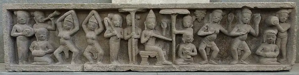 Linteau. Scène de cour. Tour sanctuaire Mỹ Sơn E4, XIe&nbsp;siècle. Grès. L. 206&nbsp;cm. Musée de Đà Nẵng[101]. Influence khmère.