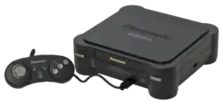 Photo d'une console noire, sur laquelle on trouve l’inscription Panasonic. Une manette est branchée à cette console.