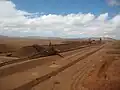 Un stacker en train de constituer un tas homogénéisation dans une mine. En arrière-plan, une excavatrice à godets en attente.