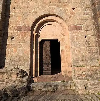 Le portail de l'église Sainte-Marie de Coustouges, construit avec une variété de pierres locales - granit gris et granit rose, conglomérat de couleur lie-de-vin, et grès[12]