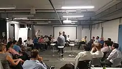 photo d'une salle dans une entreprise où des personnes sont assises en cercle.