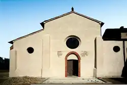 Photographie couleur d'une façade d'église très dépouillée, avec un porche surmonté d'un oculus