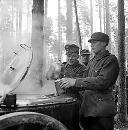Photo noir et blanc d'un groupe de soldats dans la neige, près d'une cuisine mobile, en train de se servir dans des gamelles.