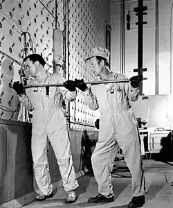Ouvriers utilisant une tige pour pousser des barres d’uranium dans la face de chargement en béton du réacteur graphite X-10.