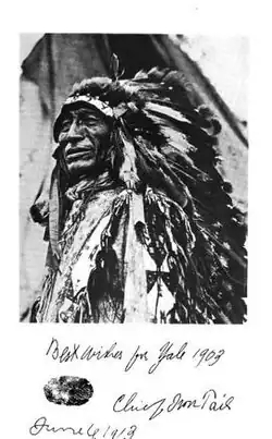 Un homme âgé, en costume traditionnel amérindien, avec une coiffe à plumes.