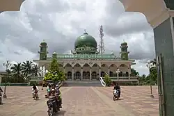 Le parvis est richement décoré avec seulement 3 motos y circulant. La mosquée est constituée de 2 tours sur les côtés et un dôme central de couleur verte.