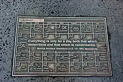 Plaquette en métal au sol sur laquelle on peut lire, en anglais, everything is only for a day both that which remembers and that which is remembered.