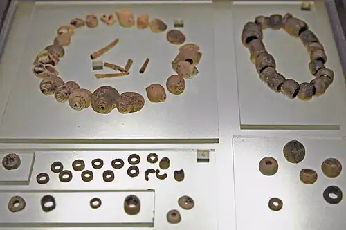 Coquillages perforés, perles de calcaire et de variscite[44]. Tumulus A, niveau supérieur, IVe&nbsp;millénaire.