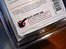 Un double coque à bords striés contient une étiquette sur laquelle est écrit Easy Open Tab, c'est-à-dire « languette facile à ouvrir »