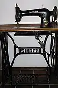 Une machine à coudre de marque Singer : le meuble supporte la machine.