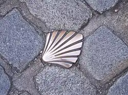 photographie d'une coquille Saint-Jacques en cuivre insérée dans les pavés d'une rue de Limoges et marquant le passage de la Via Lemovicensis menant à Saint-Jacques de Compostelle