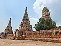 Enceinte de la Galerie couverte (Phra Rabiang) avec de fausses-fenêtres à barreaux et à l'intérieur derrière un arbre le Grand prang central