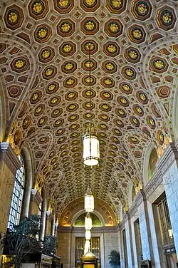 Photographie d'un plafond voûté avec des dorures où sont suspendues des lampes
