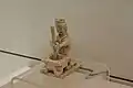 Figurine en terre cuite. Potier en train de pilonner des matériaux pour la céramique, dans un mortier.