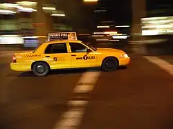 Taxi américain potographié la nuit, voiture de couleur jaune, sur un fond flou indiquant un déplacement du véhicule.