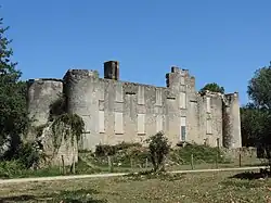 Façade d'un manoir en ruine, encadré de tourelles d'angle et de tours. Fenêtres murées.