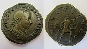 Sesterce de Gordien III, représenté au droit tête laurée, le revers porte la mention « virtus augusti », et représente l'empereur avançant à droite, tenant une lance et un bouclier pour combattre les ennemis de l'empire.