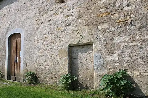 Porche latéral et ancienne porte murée surmontée d'un chrisme.