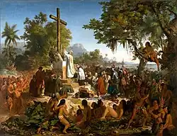 Peinture en couleurs. Une grande croix en bois, positionnée sur un autel au milieu de la nature, est entourée de plusieurs groupes de personnes. À son pied, des religieux et des soldats chrétiens sont en train de prier. Tout autour d'eux, des indigènes, vêtus de pagnes, assistent à la scène, debout, assis, ou jonchés sur un arbre.