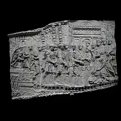 Photographie en noir et blanc d'un bas-relief représentant des personnages et des monuments.