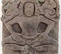 Personnage masculin: yakṣa ? Bas-relief. Trà Kiệu, c. VIe&nbsp;siècle. Grès. H0,68 x L0,70 x P0,16&nbsp;cm. Musée de Đà Nẵng[55]