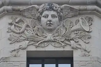 Mascaron de Mercure à l'angle des façades. Photographiée le 10 mai 2026.