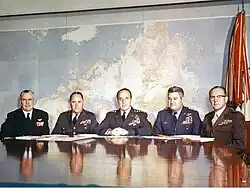 Un groupe de cinq hommes en uniforme militaire assis à une table.