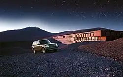 Photographie montrant une Land Rover devant l'hôtel, durant une nuit étoilée.