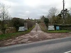 photo d'un portail blanc et d'un chemin menant à une bâtisse.