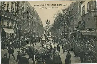 Photo du cortège avec un char, tiré par quatre chevaux, porteur d'un paysage au milieu duquel se trouve le bœuf gras