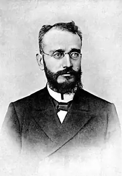 photographie noir et blanc : un homme barbu à lunettes.