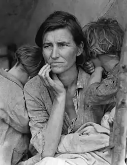 Photographie noire et blanc, une jeune mère les yeux dans le vague et deux enfants dont on ne voit pas le visage.