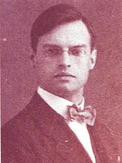 Jeune homme élégant à la mâchoire carrée, qui porte les cheveux coiffés sur le côté, un lorgnon à chaine et un nœud papillon.