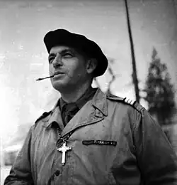 Photographie en noir et blanc d'un homme en uniforme portant un béret et fumant une cigarette.