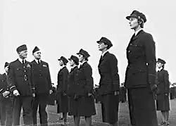 Photo en noir et blanc montrant des hommes et des femmes en costume militaire sombre.