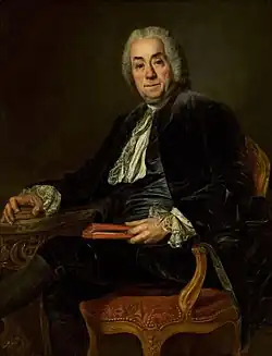 Peinture. En buste, de trois quarts, assis dans un fauteuil, un livre à la main.