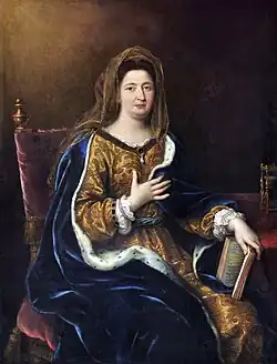 De face, femme richement vêtue, assise, main droite sur la poitrine, main gauche tenant un livre entrouvert.