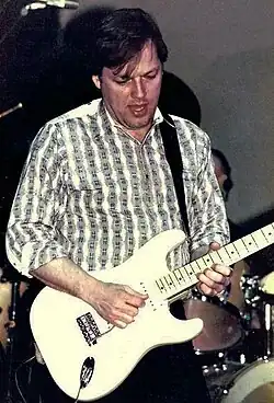 Photo d'un homme en chemise jouant de la guitare électrique
