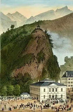 Tableau montrant une foule près d'un bâtiment blanc, à l'arrière une colline avec un kiosque, au fond des montagnes