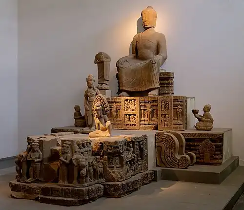 Bouddha du vihara (la pose des mains est un emprunt à la Chine des Tang) et assemblée bouddhique[75]. À droite, moine porteur d'offrande. Fragments, Đồng Dương. Fin IXe - début Xe&nbsp;siècle.Musée de Đà Nẵng
