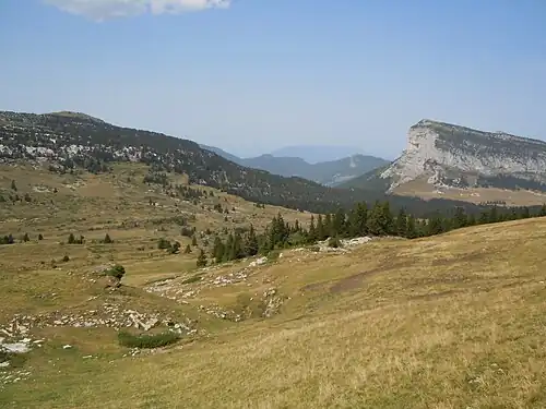 un vallon couleur automnale avec une barre de falaise au fond