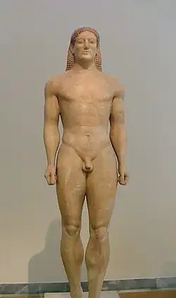 Photo d'une statue de couleur ocre représentant un jeune homme entièrement nu se tenant au garde-à-vous.