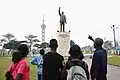 La statue de Patrice Lumumba avant la construction du mausolée avec en arrière-plan la tour de l'Échangeur.