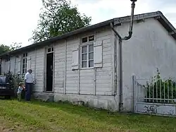 Une maison blanche à un seul niveau, à panneaux de bois.