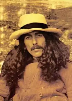Photo-portrait en sepia d'un homme aux cheveux et à la barbe longs, avec un chapeau.