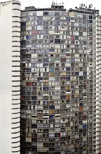 Vue de la façade. Les différentes fenêtres et leurs rideaux colorés ressemblent à une mosaïque.