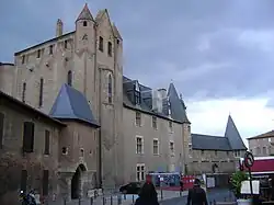 Bâtiment en briques rouges doté de fenêtres à meneaux et toitures pentues en ardoise et lucarnes de toiture.