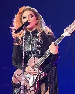 Lady Gaga en concert, jouant de la guitare.