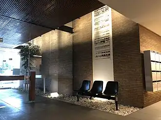 Photographie du chimigramme de Pierre Cordier, oeuvre d'art avec tâches noires sur fond blanc. En premier plan, fauteuils plastique, dalle béton, porte vitrée
