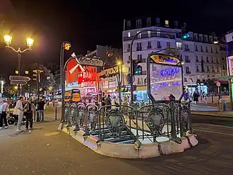 Vue nocturne avec le Moulin Rouge à l'arrière-plan.